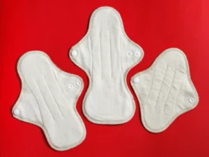 An image of reusable cloth pads and disposable sanitary napkins side by side, symbolizing the choice between eco-friendly and traditional menstrual products.